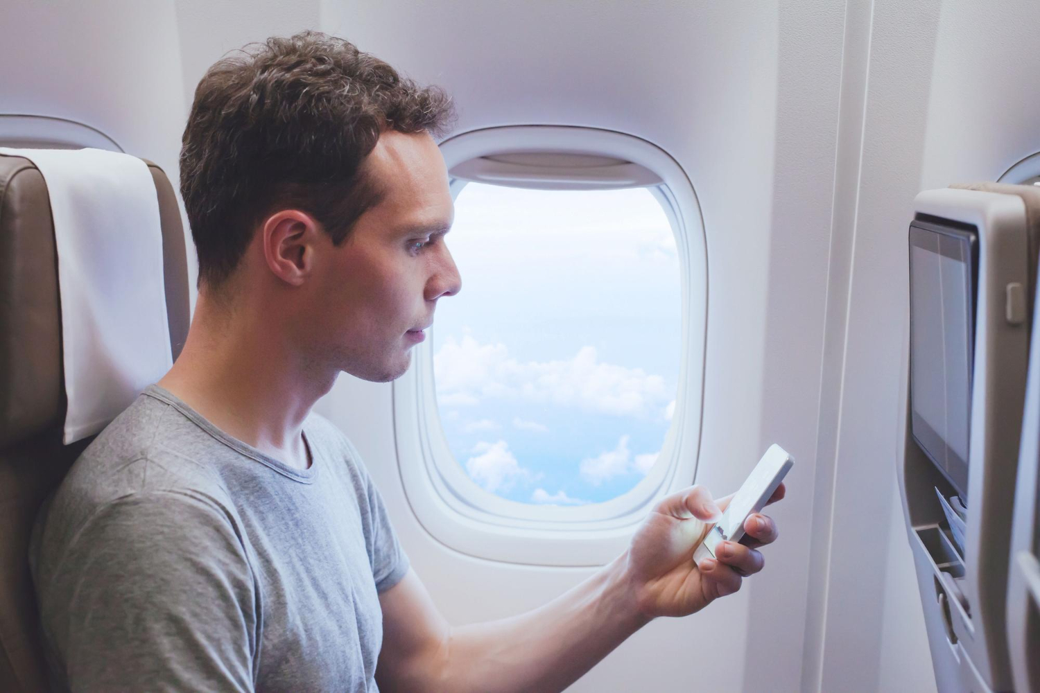 man using phone in plane